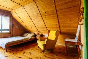 1 dormitorio en una cabaña de madera con 1 cama y 1 silla en Domek pod bukami, en Szymbark