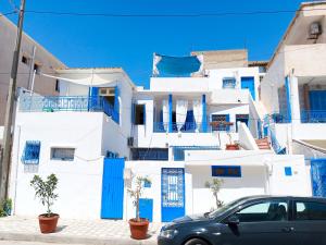 a car parked in front of a white building at Les Sables Bleus in Le Kram
