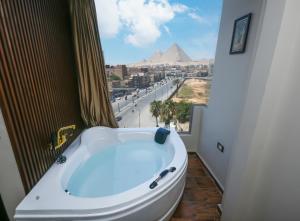 uma banheira na casa de banho com vista para as pirâmides em Rotana Pyramids View em Cairo