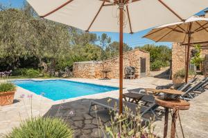 an external view of a pool with chairs and an umbrella at The Old Cottage - Cas Julians Sencelles Ruberts in Sencelles
