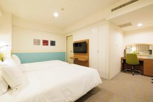 a hotel room with a white bed and a desk at ANA Holiday Inn Sapporo Susukino by IHG in Sapporo
