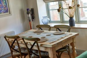 a dining room table with four chairs and a vase at Spacious 2 Bedroom Coach House in Cley Norfolk in Cley next the Sea +12 photos