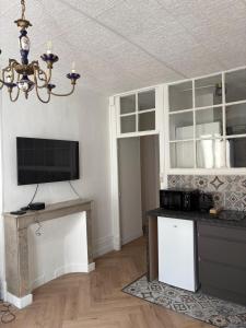 a living room with a tv and a chandelier at Agate - En plein coeur de la ville Dijon in Dijon