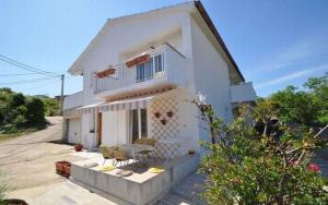 a white house with a porch and a balcony at Apartment Vrbnik 8 in Vrbnik