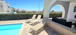 a group of chairs sitting next to a swimming pool at Agia Thekla bungalow with pool in Ayia Napa