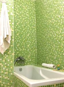 a green tiled bathroom with a tub and a towel at Casa Encosta da Lagoa in Foz do Arelho