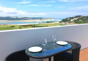 una mesa con 2 copas de vino en el balcón en Casa Encosta da Lagoa, en Foz do Arelho