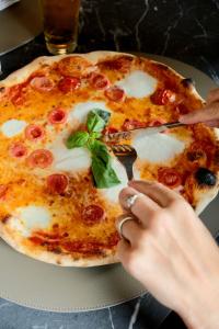 a person cutting a pizza with a fork and knife at Smart Hotel King, by R Collection Hotels in Varedo +33 photos