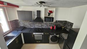 a kitchen with black cabinets and a stove top oven at La Suite Rouge Proche Paris & Stade De France in Drancy +5 photos