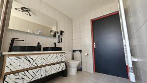 a bathroom with a toilet and a blue door at La Suite Rouge Proche Paris & Stade De France in Drancy
