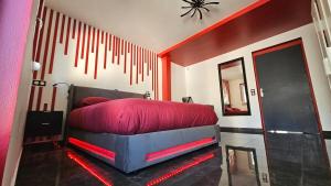 a bedroom with a bed with red sheets and a mirror at La Suite Rouge Proche Paris & Stade De France in Drancy