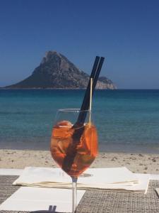 a drink in a glass sitting on a table near the beach at HOTEL Al FARO , SPIAGGIA LA CINTA ,SAN TEODORO in San Teodoro