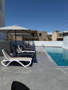 a row of lounge chairs and an umbrella next to a pool at Suar Apartment in Ksamil