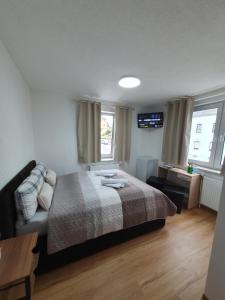 a bedroom with a bed and a table and two windows at Pension Valentina in Mühlau