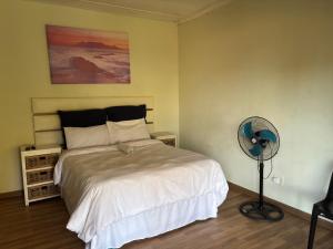 a bedroom with a white bed and a fan at Hlalanathi Lodges - 25 North Drive Margate in Margate