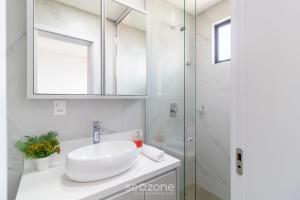 ein weißes Badezimmer mit Waschbecken und Dusche in der Unterkunft Apto Novo a 150m da Praia de Pereque CLE1202 in Perequê + 25 Fotos