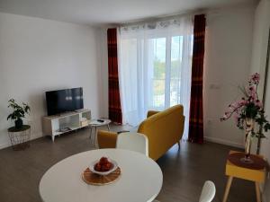 a living room with a table and chairs and a tv at Résidence NOVAGE - Amiens in Amiens
