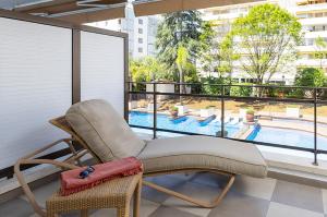 a chair on a balcony with a view of a pool at Suites del Mar Fenals Apartments in Lloret de Mar