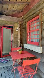 Una mesa roja y dos sillas en el porche de una cabaña. en T2 Bungalow, en Estorãos 17 fotos más