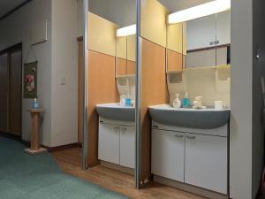un bagno con due lavandini e uno specchio di 旅館青柳 海越し立山連峰の雪山絶景で休もう a Himi