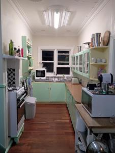 una cucina con armadi verdi e bianchi e un lavandino di Albert Road Cottage - late art deco 3 bedroom house and caravan a Bunbury