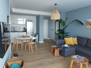 Una sala de estar con un sofá azul y una mesa. en Benny's Beach House 2, en Zandvoort