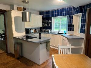 a kitchen with white cabinets and a blue tiled wall at Heron House in Warwick