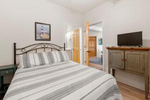 Un dormitorio con una cama y un televisor de pantalla plana. en Under The Boardwalk, en Kill Devil Hills