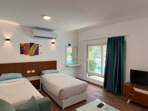 a hotel room with two beds and a television at Family Chalet Pool & Aqua-Park Access in Sharm El Sheikh in Sharm El Sheikh