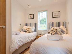 a bedroom with two beds and a window at 2 Tree Tops in Looe