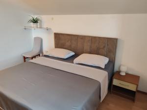 a small bedroom with a bed and a chair at Apartments Borovina in Bol