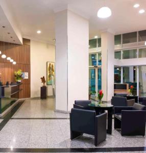 eine Lobby mit Stühlen und einem Tisch in einem Gebäude in der Unterkunft ApartHotel Centro de Nova Iguaçu in Nova Iguaçu