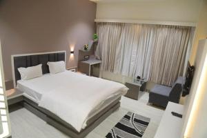 Un dormitorio con una gran cama blanca y una silla. en Hotel KV Pride, en Mehekar