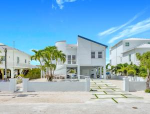 キーラーゴにあるKeys Harbor - Waterfront, Private Boat Dock, Outdoor Oasisのヤシの木が目の前に広がる白い家