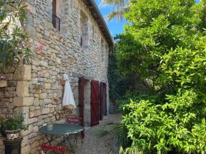 a stone building with a door and a table and a umbrella at Chambres d'hotes lecortile in Villeneuve-lès-Maguelonne