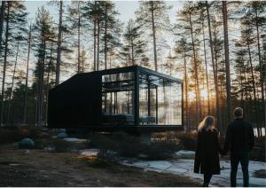 a couple standing in front of a glass house at Balder Luxury Lodge & Glass Igloos in Levi