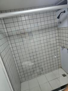 a bathroom with a shower with white tile at Apartamento econômico Garvey Hotel in Brasilia +2 photos