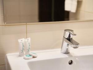 a bathroom sink with a faucet and two toothbrushes at Hotel Biały Dwór in Okuninka +14 photos