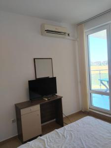 a bedroom with a bed and a tv and a window at 2 Room Apartment Costa Calma Aheloy Bulgarien in Aheloy