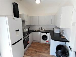Una cocina con un frigorífico blanco y un lavavajillas. en 4 Bedroom House 8min walk to EastHam Station, en Londres
