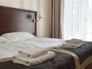 a bed with towels sitting on top of it at Hotel Biały Dwór in Okuninka