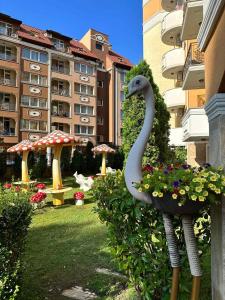 Una estatua de un cisne en un jardín con edificios. en Sweet Home, en Sunny Beach