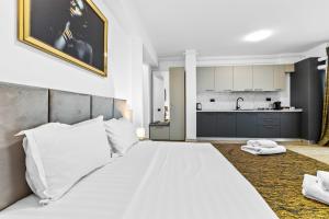 a bedroom with a large white bed and a kitchen at One SeaView std in Infinity Pool & Spa Resort in Mamaia Sat/Năvodari