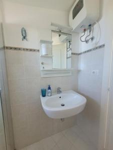 a white bathroom with a sink and a mirror at Villa Stella in Fontane Bianche