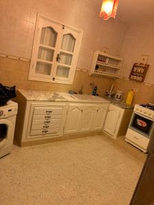 a kitchen with white cabinets and a sink and a stove at Villa flamant rose in Djerba