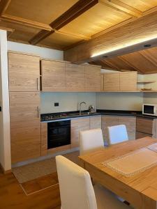 a kitchen with wooden cabinets and a wooden table with chairs at Sappada Family Apartments in Sappada