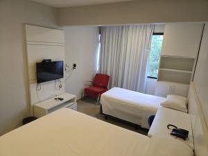 a hotel room with two beds and a red chair at Apartamento econômico Garvey Hotel in Brasilia