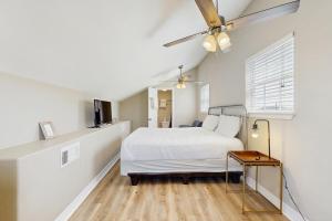 a bedroom with a white bed and a ceiling fan at Sunset Palms in Galveston