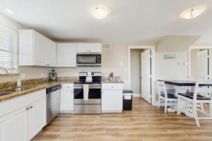 a kitchen with white cabinets and appliances and a table at Sunset Palms in Galveston +15 photos