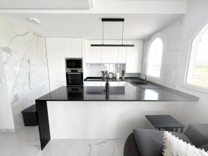 Una cocina con gabinetes blancos y una encimera negra. en Casa Anita - Hacienda Riquelme Golf Resort, en Sucina